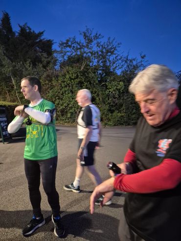 Three men in athletic wear standing outside during dusk.