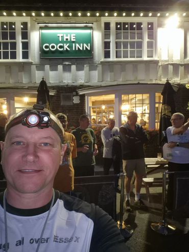 Man taking selfie outside The Cock Inn pub at night.