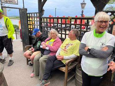 A group of elderly people in casual clothing relaxing on benches outdoors.