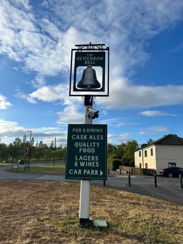 Signpost for The Retendon Bell pub and dining with menu highlights and car park direction.