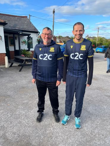 Two men in matching sportswear standing outdoors on a sunny day.