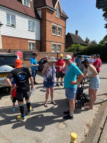 Group of people chatting outside a brick building on a sunny day.