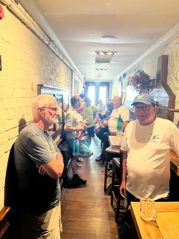 A group of men socializing in a narrow pub corridor.