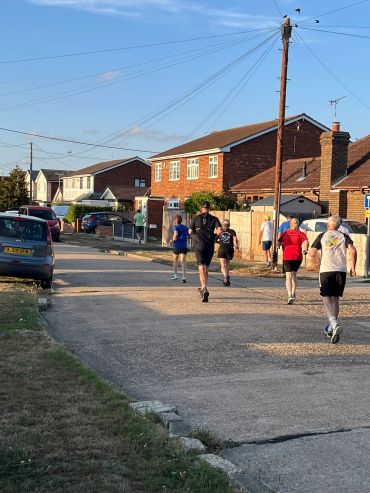 People jogging on a suburban street in the evening.