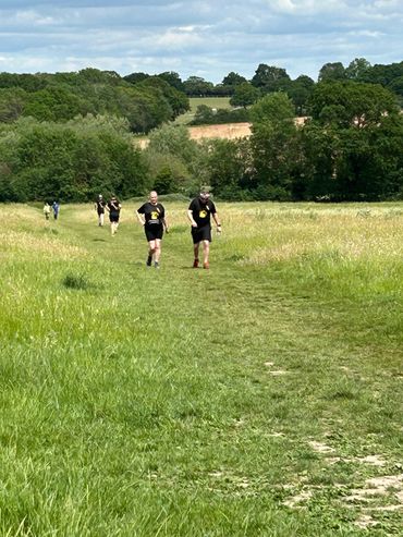 People running on a grassy trail in a countryside setting.