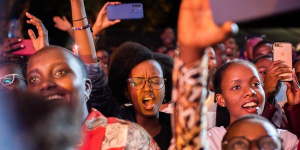 Excited crowd at a lively event, people cheering and capturing moments on phones.
