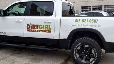 White RAM truck with Dirt Girl Landscaping logo and contact info on the side.