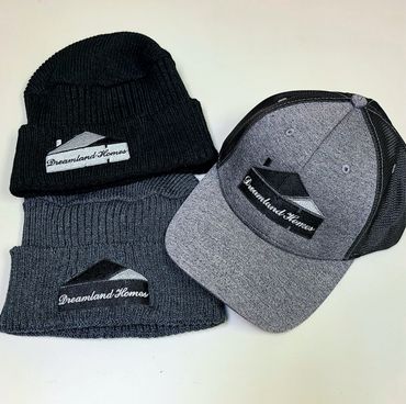 Two knit beanies and a mesh-back cap with Dreamland Homes logo.