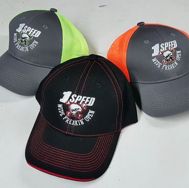 Three colorful caps with "1 Speed Wide Freakin Open" and skull designs.
