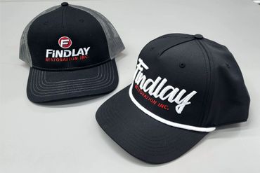 Two black baseball caps with "Findlay Restoration Inc." logos embroidered in white and red.