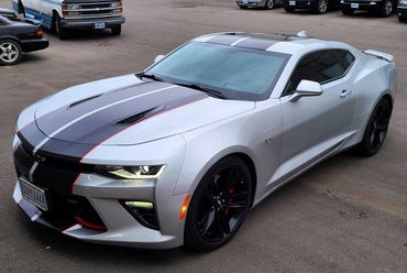 Silver sports car with black and red racing stripes parked outdoors.