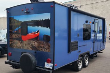 Fiberglass RV trailer wrapped from beige to gloss metallic blue.