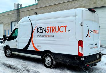 White Kenstruct Ltd. branded van parked on snowy ground near a building.