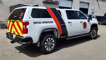 White special operations truck with red and yellow chevron pattern on the back.