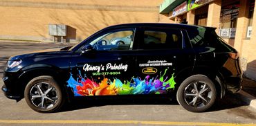 Black car with vibrant paint splash design and Nancy's Painting advertisement.
