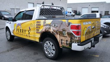 Perry's Roofing truck with bright yellow advertisement and house image wrap.