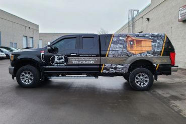 Black truck with signage for Rob's Amish Built Sheds and contact information.