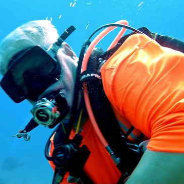 A Squirrel in an orange rashguard underwater with diving gear.