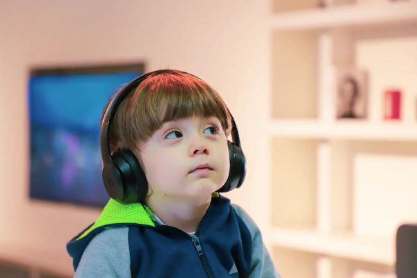 Young boy wearing headphones, looking up.