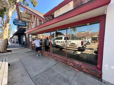 Two men standing outside a coffee shop on a sunny day.