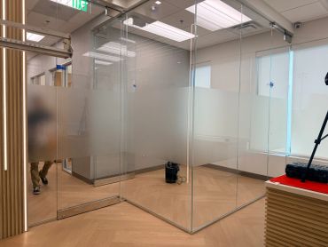 Modern office space with glass partitions and wooden floor.