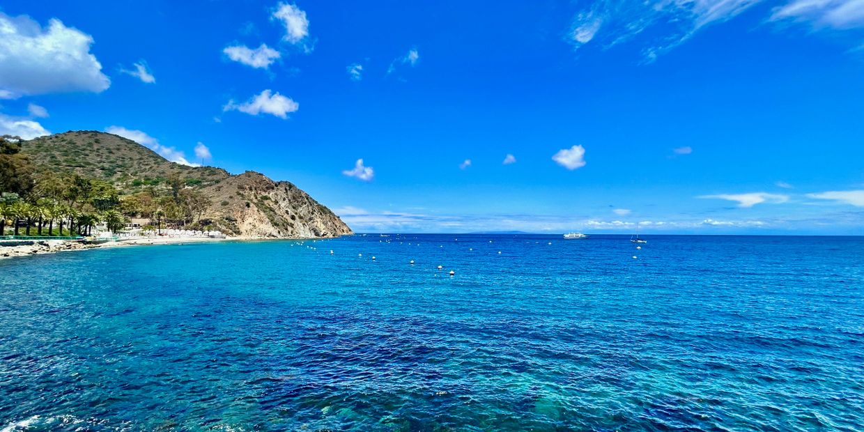 Bright blue ocean with hills and a clear sky on a sunny day.