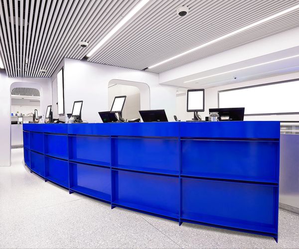 Modern reception desk with blue panels and computer monitors in a bright office.