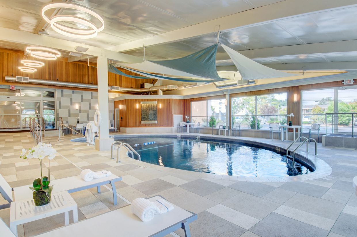 Modern indoor pool with lounge chairs and decorative ceiling sails.