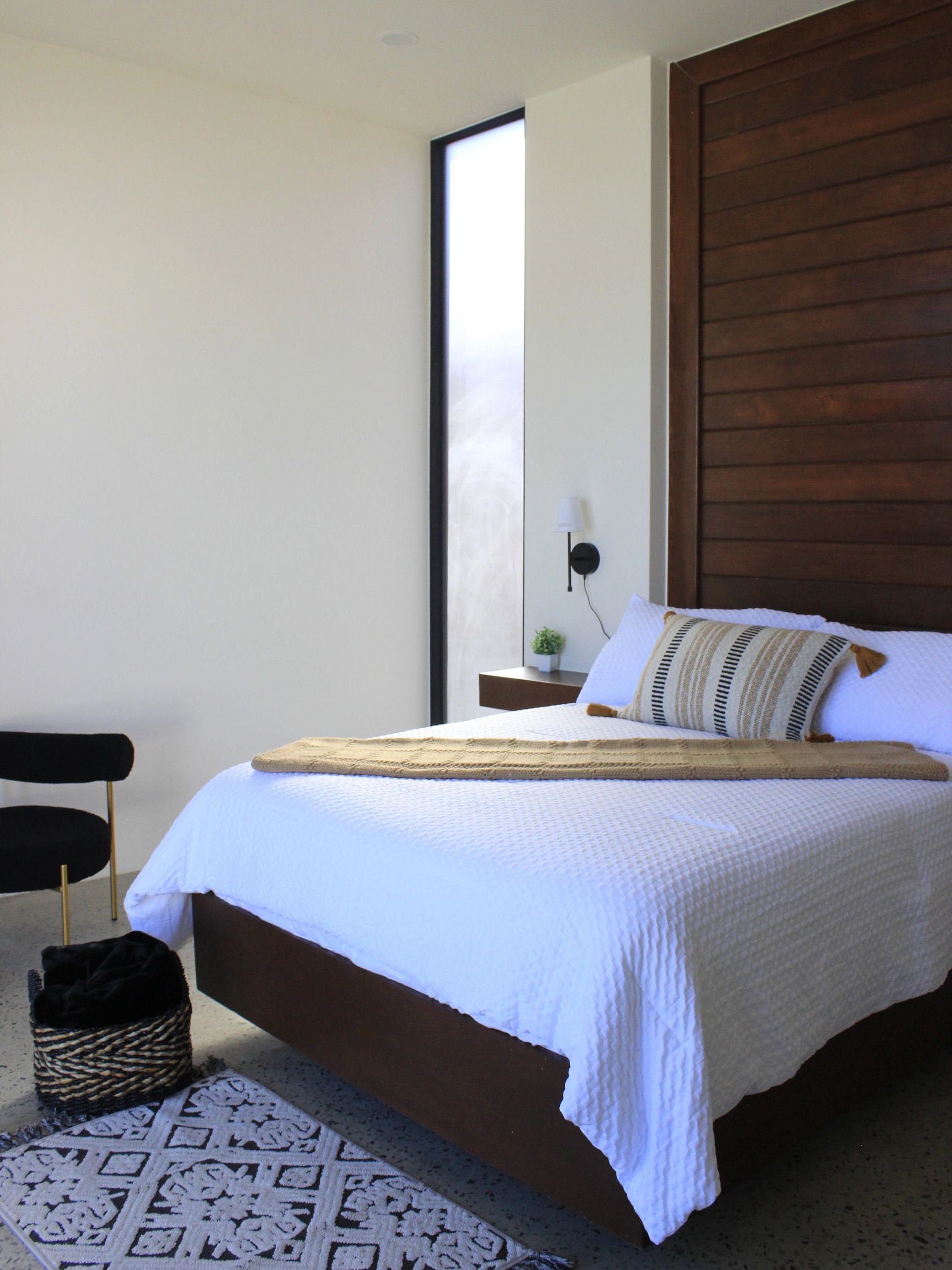 Modern bedroom with white bedding and wooden accents.