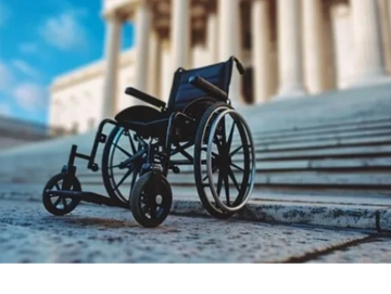 Picture of a wheelchair at the bottom of a staircase at a government building.