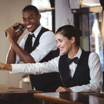 Two bartenders working together happily.