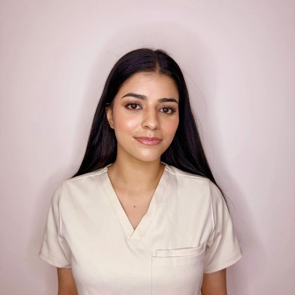 Young woman with long black hair wearing a cream scrub top.