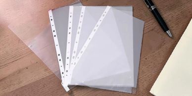 Clear plastic sheet protectors fanned out on a wooden surface.