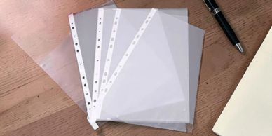 Clear plastic sheet protectors fanned out on a wooden surface.