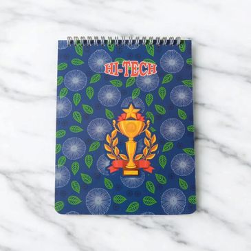 A blue floral notebook with a trophy and 'HI-TECH' text on the cover.
