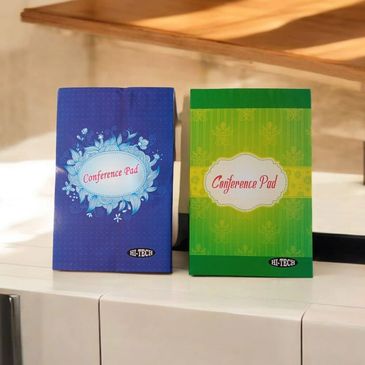 Two colorful conference pads, one blue and one green, placed on a white surface.