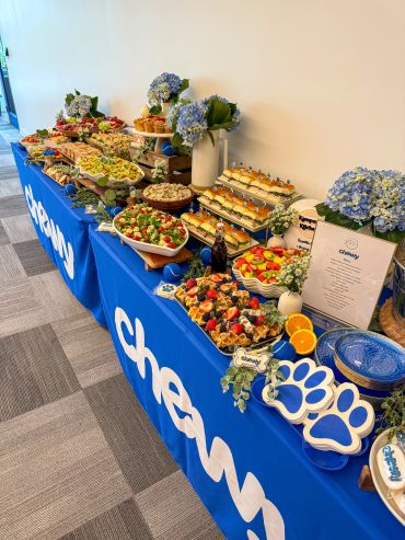 Catering spread with sandwiches and salads on a blue tablecloth.