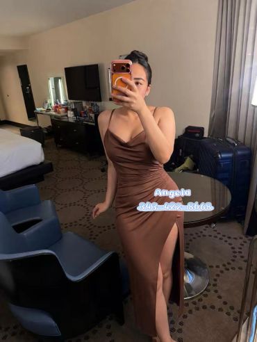 Woman in brown dress taking a mirror selfie.