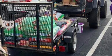 Trailer of donated bags of cat and dog food ready for distribution.