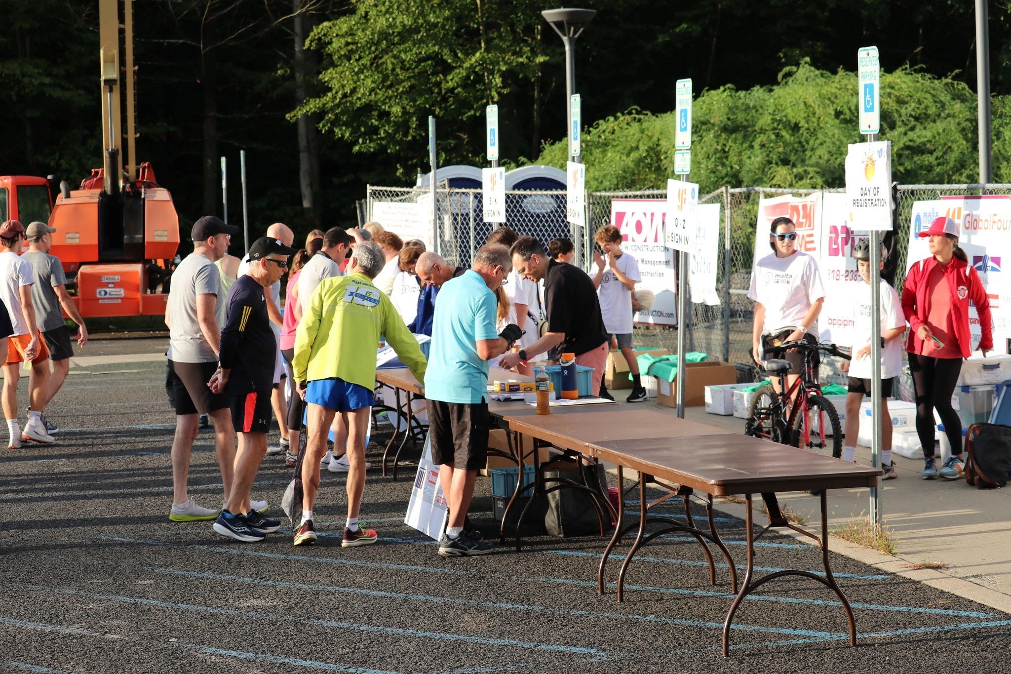 People registering at an outdoor event registration table early in the morning.