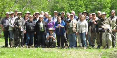 Group of people outdoors with hats and cameras, enjoying nature.