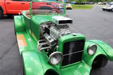Green vintage hot rod car with exposed engine.