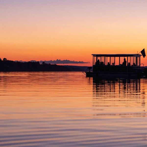 Boat silhouetted against a vibrant sunset on calm water.