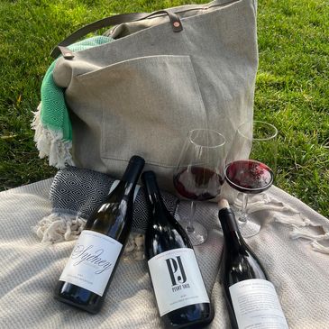 Lawson Family wines on the ground with a bag and two glasses. 