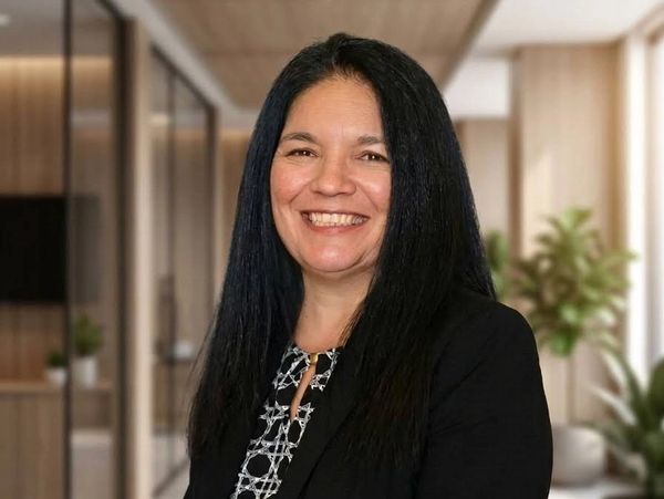 Smiling woman with long black hair in business attire in an office.