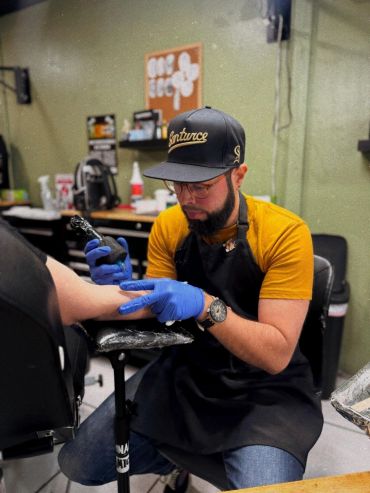 Tattoo artist focused on inking a client's arm in a studio.