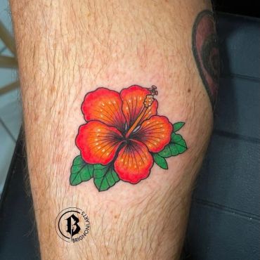 Vibrant red and orange hibiscus flower tattoo with green leaves on skin.
