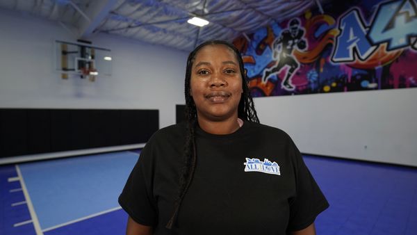 Woman in a basketball gym smiling at the camera.