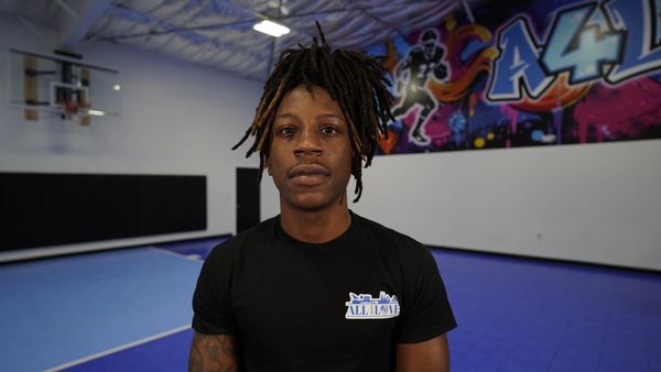 Man with dreadlocks in a gym with vibrant wall art.