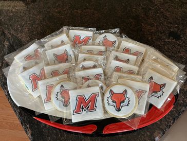 Cookies with red 'M' and fox logos individually wrapped on a tray.